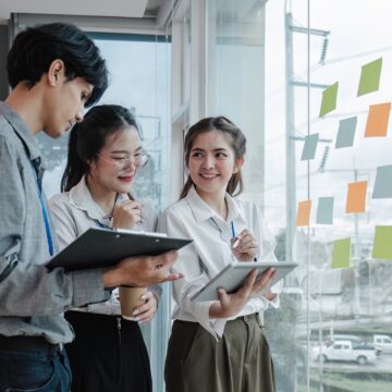 team employees busy brainstorming develop business ideas write on colorful sticky notes, concentrated colleagues share thoughts on pads on glass window Corporate vs. Entrepreneurial Career Path Post-MBA in India
